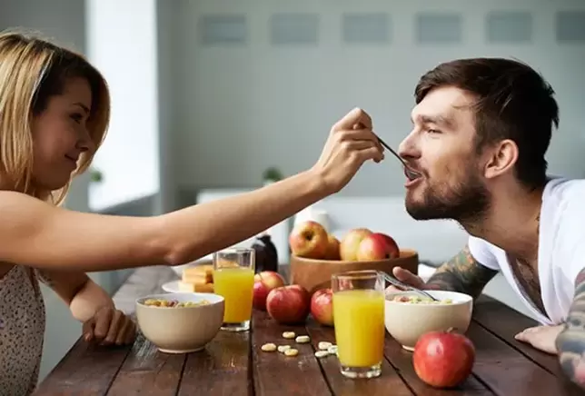 the woman feeds the man with nuts to increase her strength